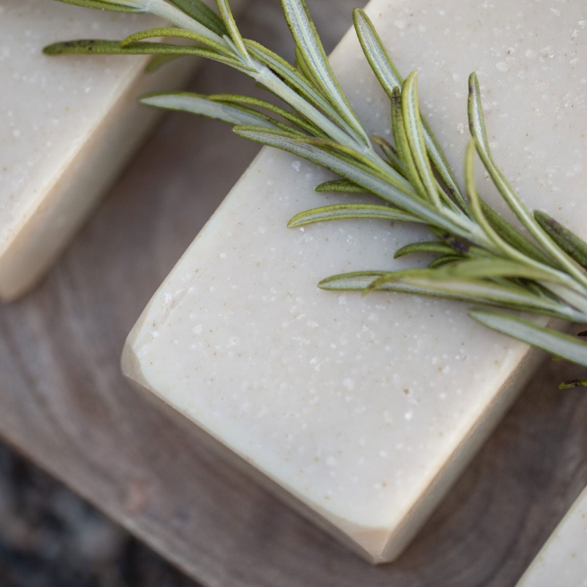 upclose of bar soap that is beige and all natural. topped with rosemary herbs