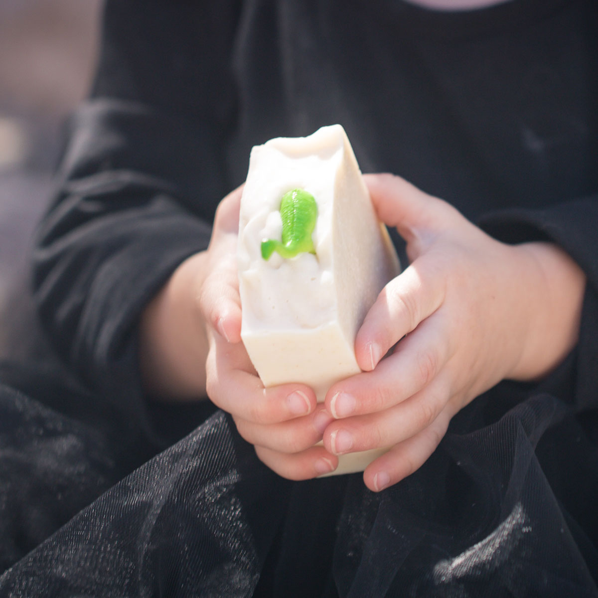 handmade bar soap embedded with a dinosaur toy held by a baby