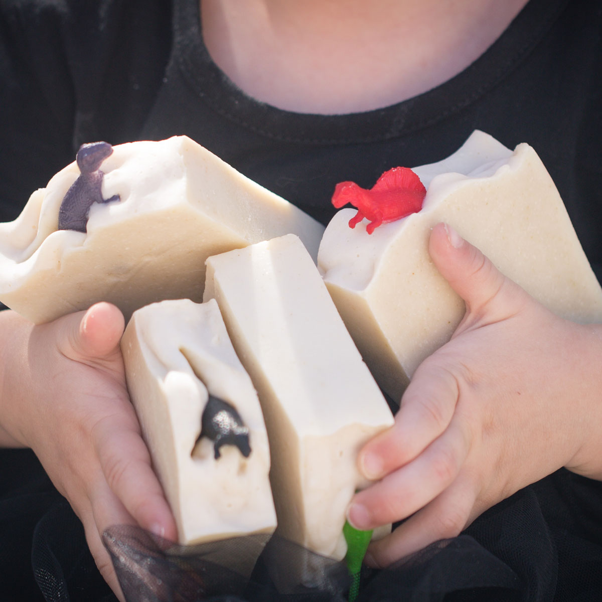 handmade bar soap embedded with dinosaur toys held by a baby